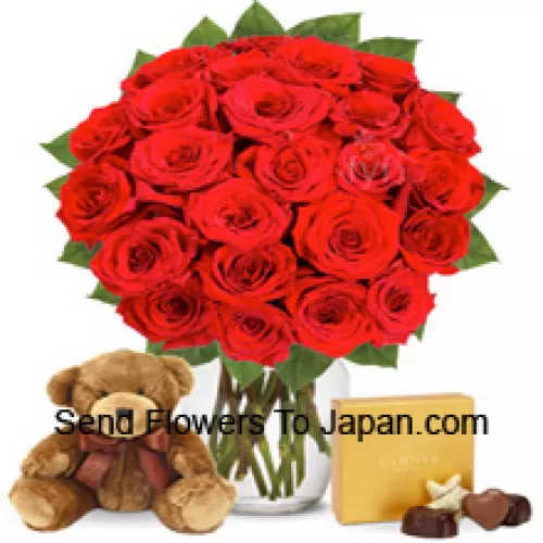 25 rote Rosen mit etwas Farn in einer Glasvase, begleitet von einer importierten Schachtel Schokolade