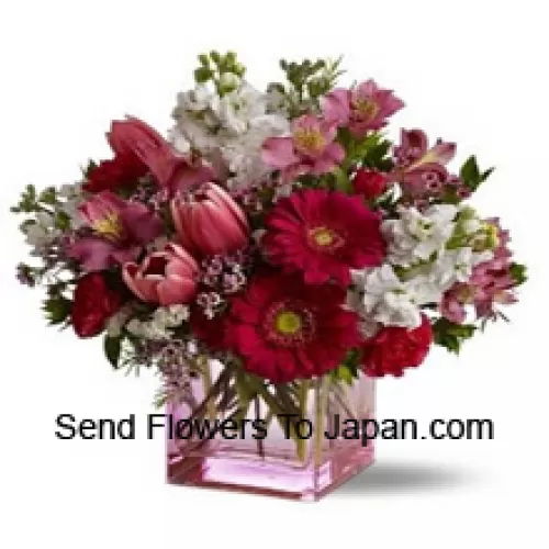 赤いバラ、赤いチューリップ、季節の詰め物を加えたアソートされた花々がガラスの花瓶に美しくアレンジされています