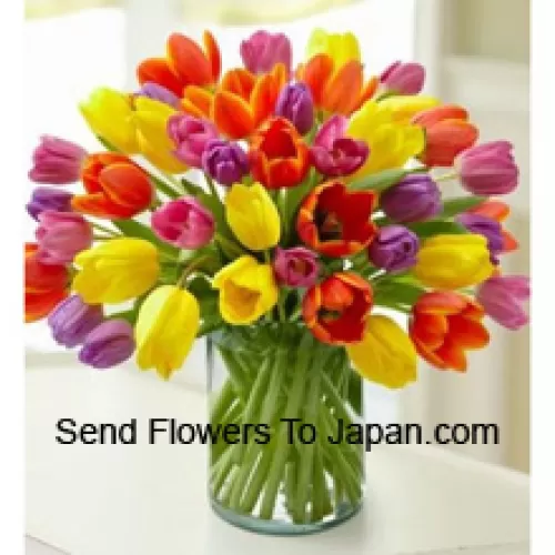 ガラスの花瓶に入ったミックスカラーのチューリップ - 季節の花が入手できない場合は、同等価値の他の花で代用されることがあります