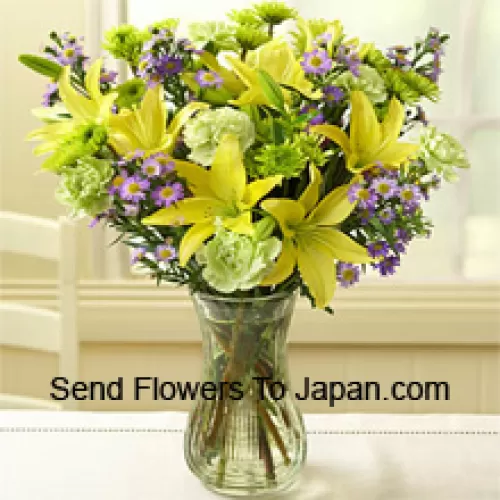 Gele Lelies en andere gevarieerde bloemen prachtig gerangschikt in een glazen vaas