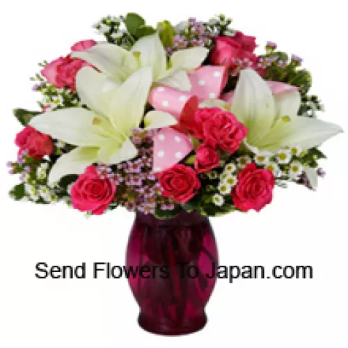 Rosas cor de rosa e lírios brancos com complementos sazonais em um vaso de vidro
