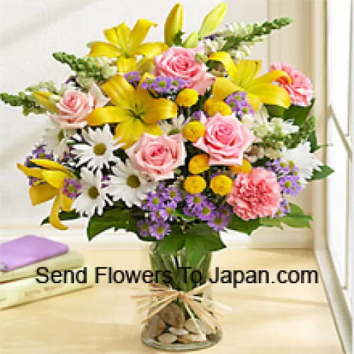 Розовые розы, розовые гвоздики, белые герберы и желтые лилии с сезонными наполнителями в стеклянной вазе