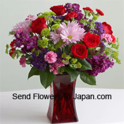 Rosas vermelhas, cravos rosa e outras flores sazonais variadas em um vaso de vidro