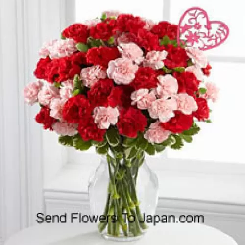 37 Garofani (19 rossi e 18 rosa) con riempitivi stagionali e bastoncino a forma di cuore in un vaso di vetro