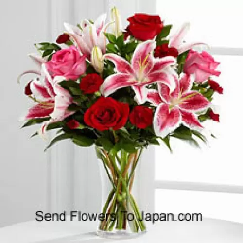 Czerwone i różowe róże z różowymi liliami i sezonowymi wypełniaczami w szklanym wazonie